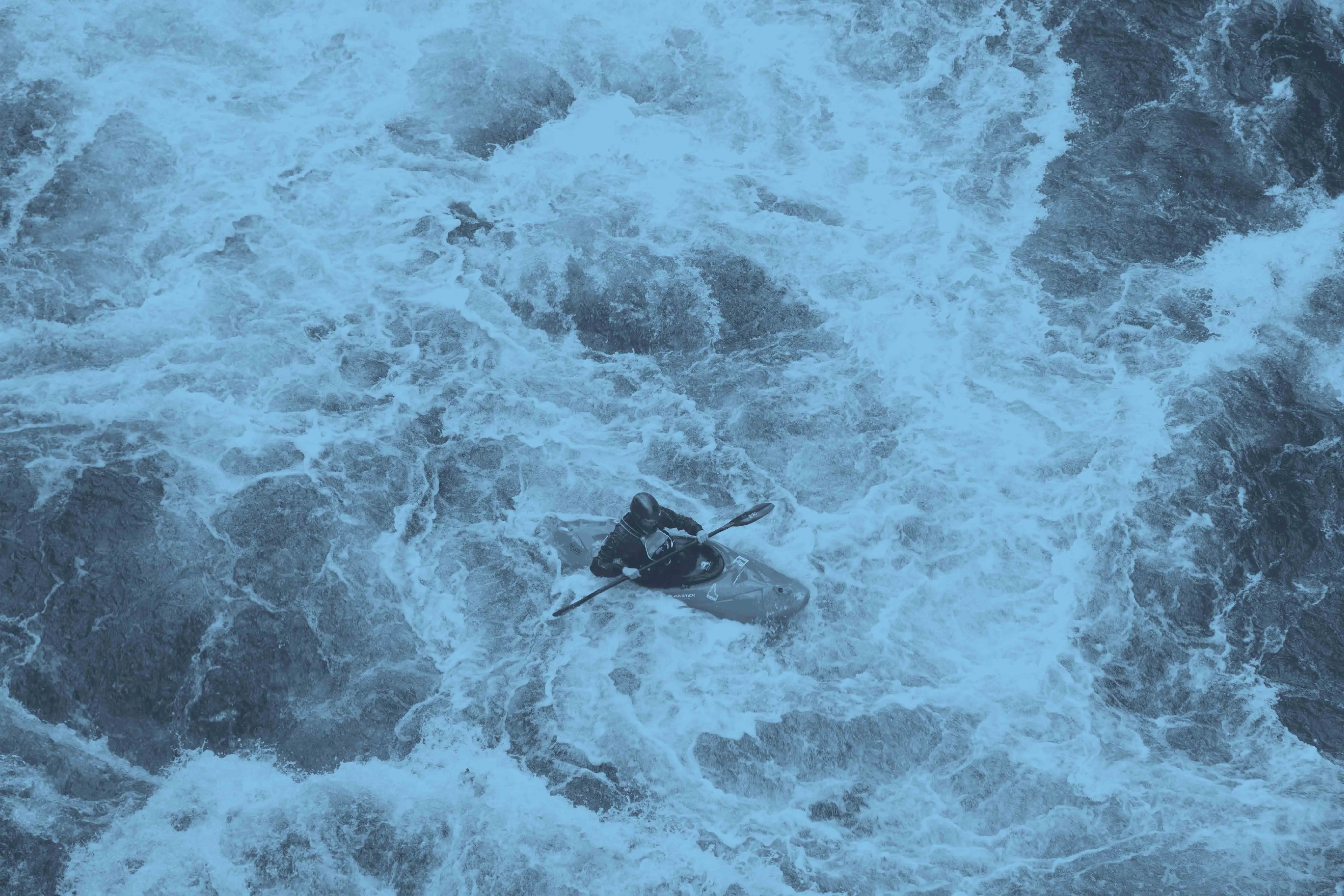 A kayaker, seen from above, paddling through white water
